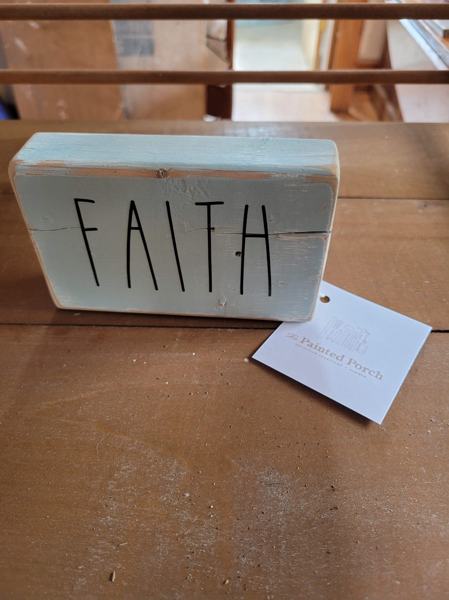Wooden block sign painted light blue and sanded. Black vinyl letters "Faith." Approximately 2" x 4" x 6"