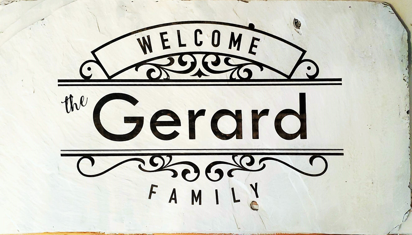 Welcome, The Gerard Family Slate Sign. The natural slate comes in a variety of sizes and this sample is approximately 10" x 16" wide. It will be painted white and laser etched with your family name. This one does not have a hanger attached because it sits on an easel, but we can attach a jute rope hanger or a wire hanger if you wish to hang your sign.