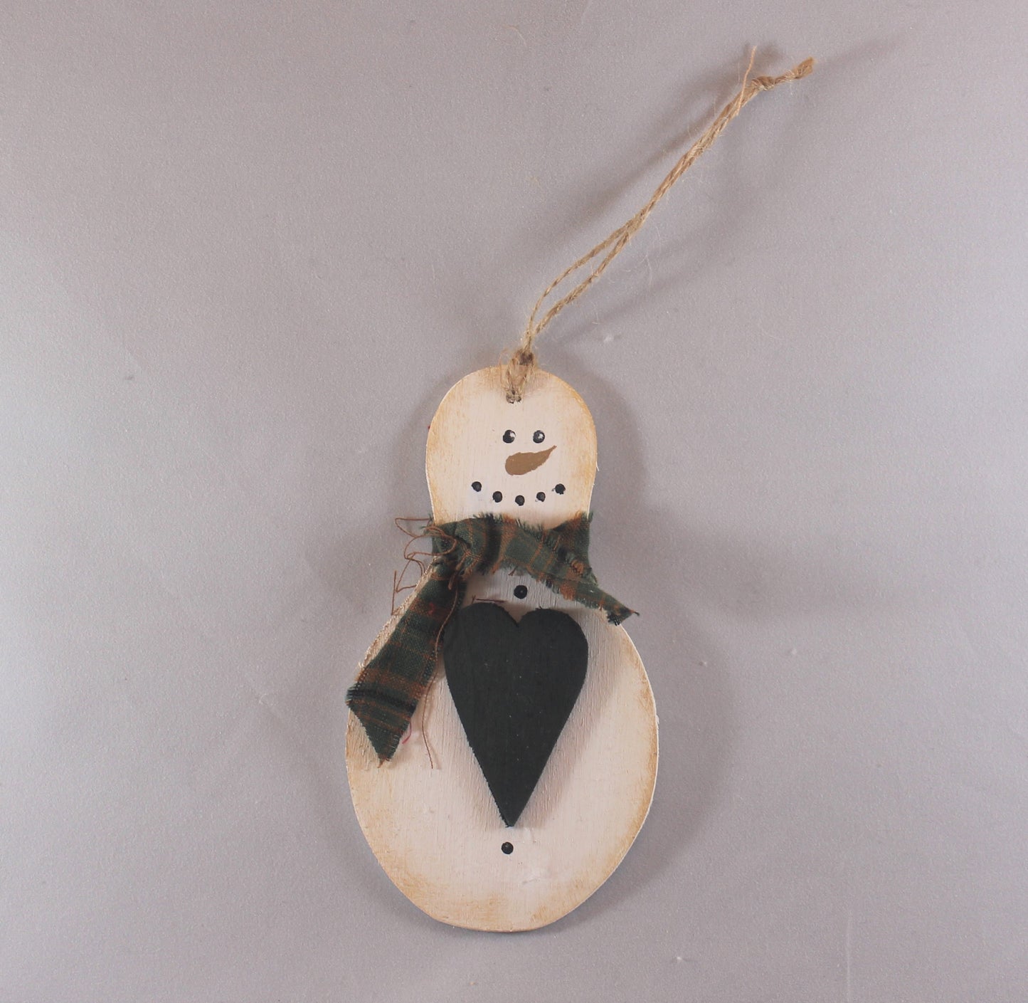 wooden hand painted snowman ornament with green fabric scarf holding heart