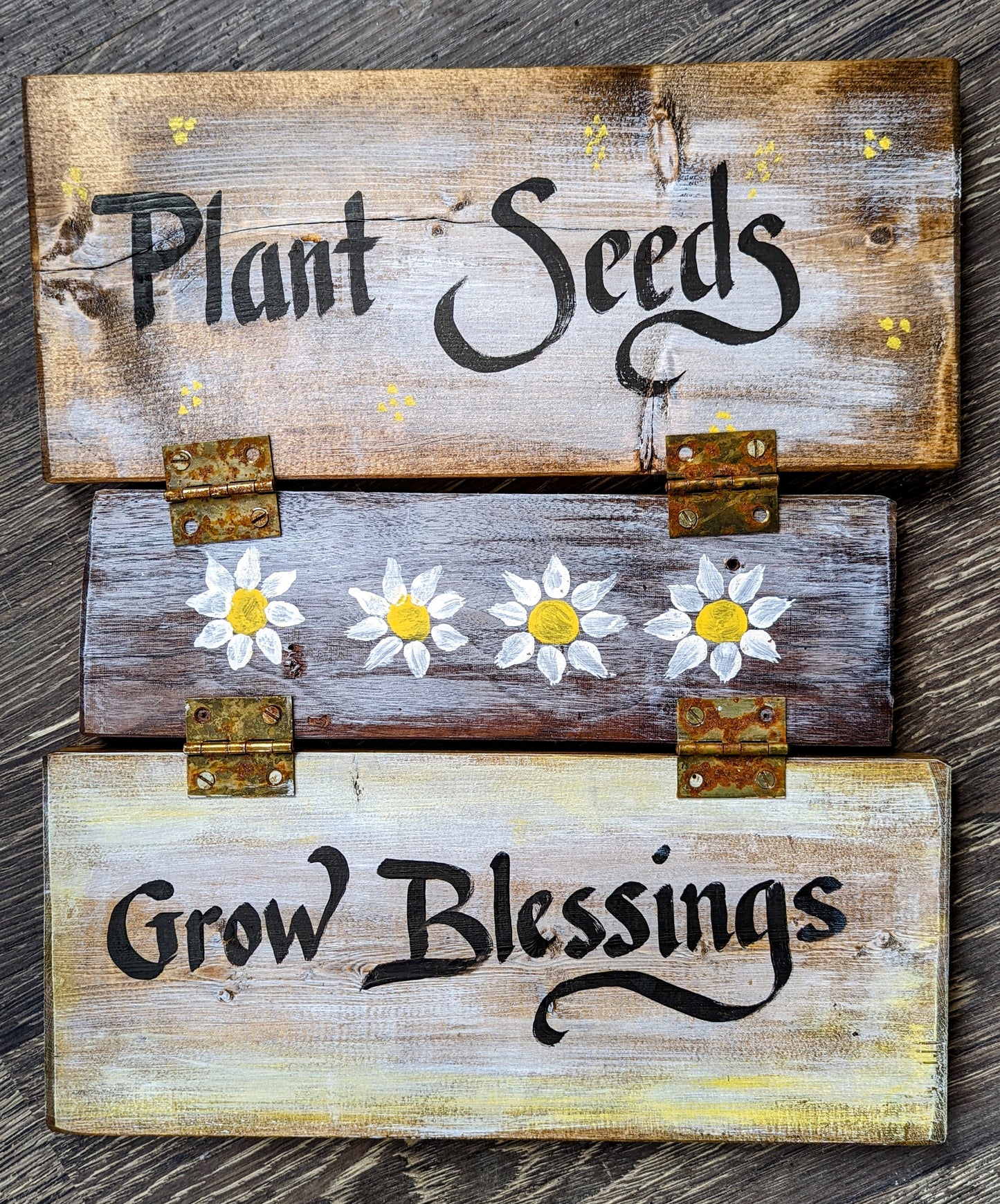 "Plant Seeds Grow Blessings" sign panels held together by hinges. the larger panels are approximately 2" x 6" x 12" hand painted happy little daisies