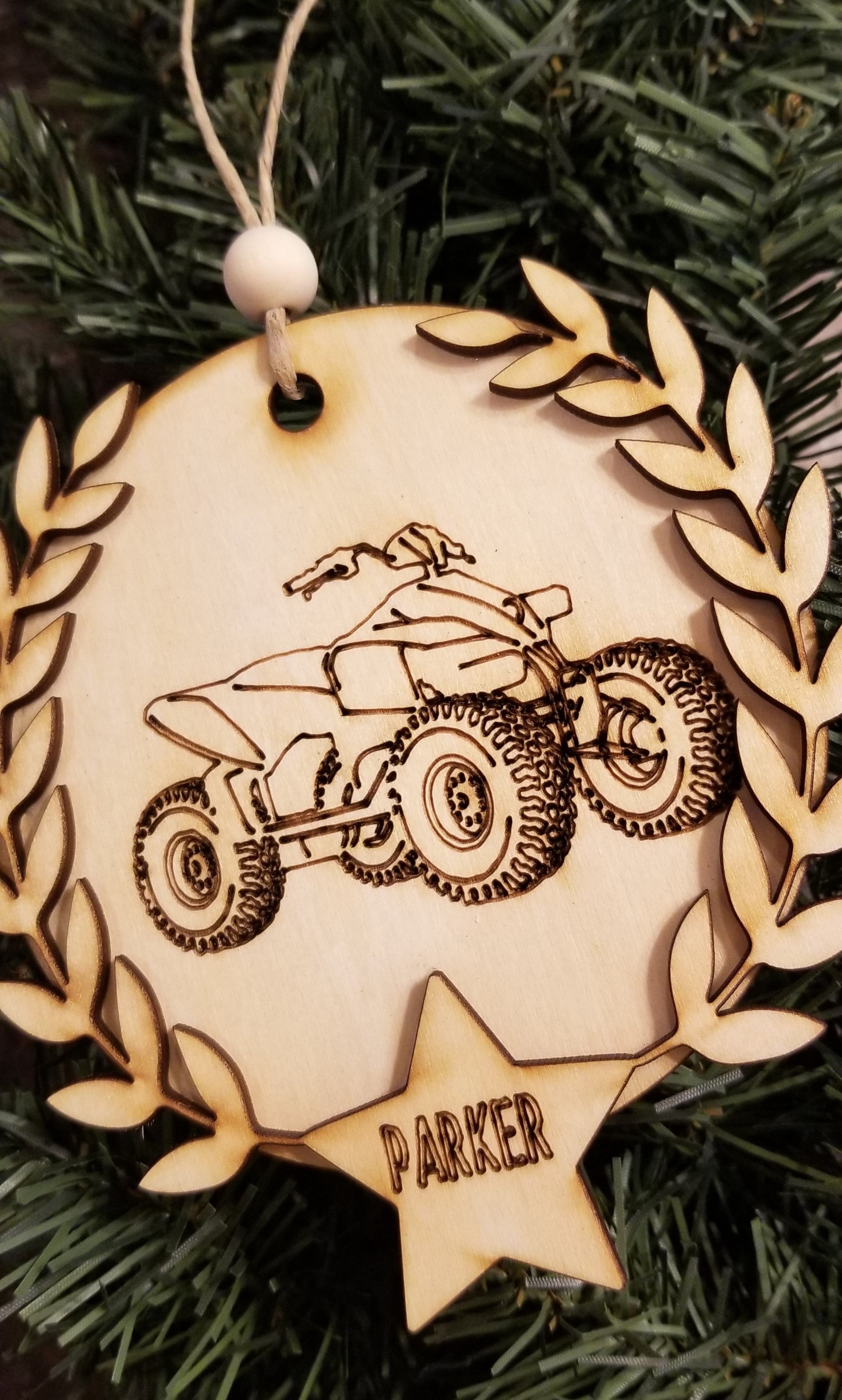 Laser cut round wooden ornaments with laser engraved dirt bike or 4 wheeler, laurel wreath, and star with name inside.