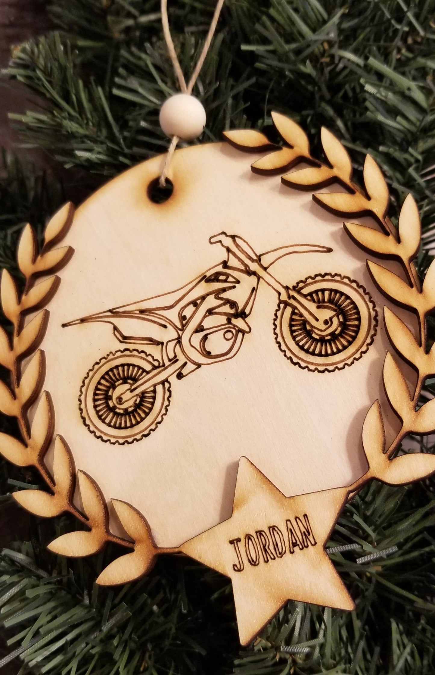 Laser cut round wooden ornaments with laser engraved dirt bike or 4 wheeler, laurel wreath, and star with name inside.