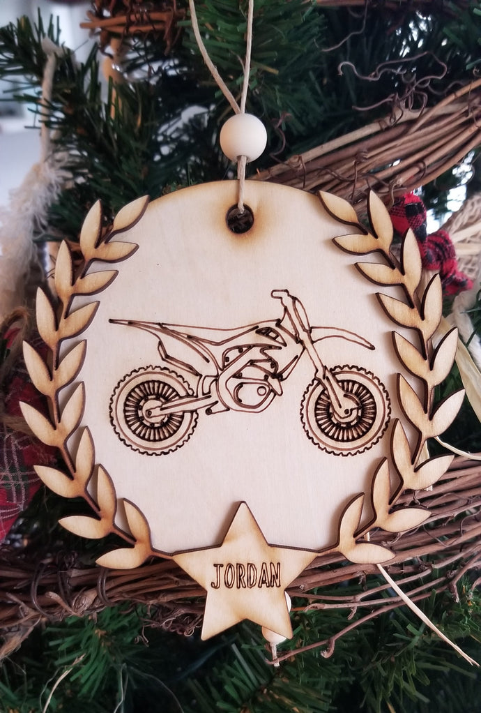 Laser cut round wooden ornaments with laser engraved dirt bike or 4 wheeler, laurel wreath, and star with name inside.