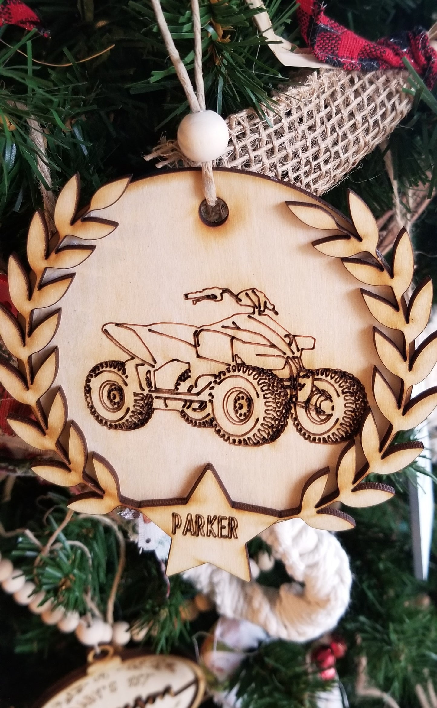 Laser cut round wooden ornaments with laser engraved dirt bike or 4 wheeler, laurel wreath, and star with name inside.