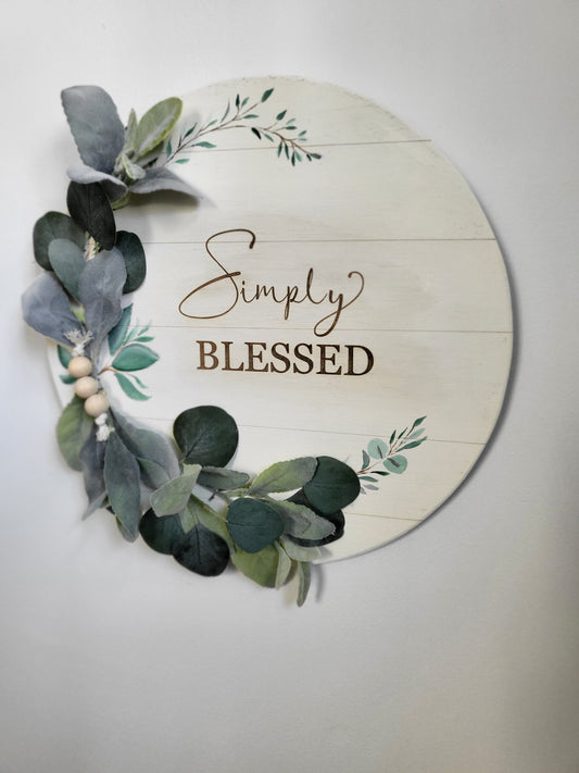 This precious round sign is "Simply Blessed." Laser engraved wood with eucalyptus and wooden beads.