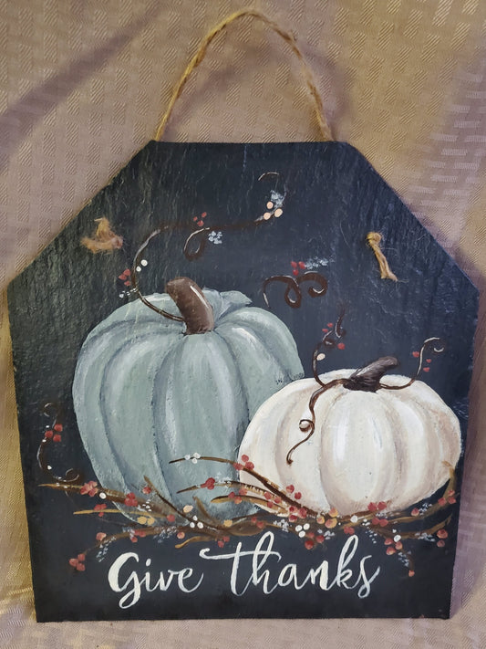 This stunning natural slate sign with hand-painted pumpkins reminds you to "Give Thanks" while adding a warm and cozy charm to your home. five sided slate, jute rope hanger, medium size 11" x 12"