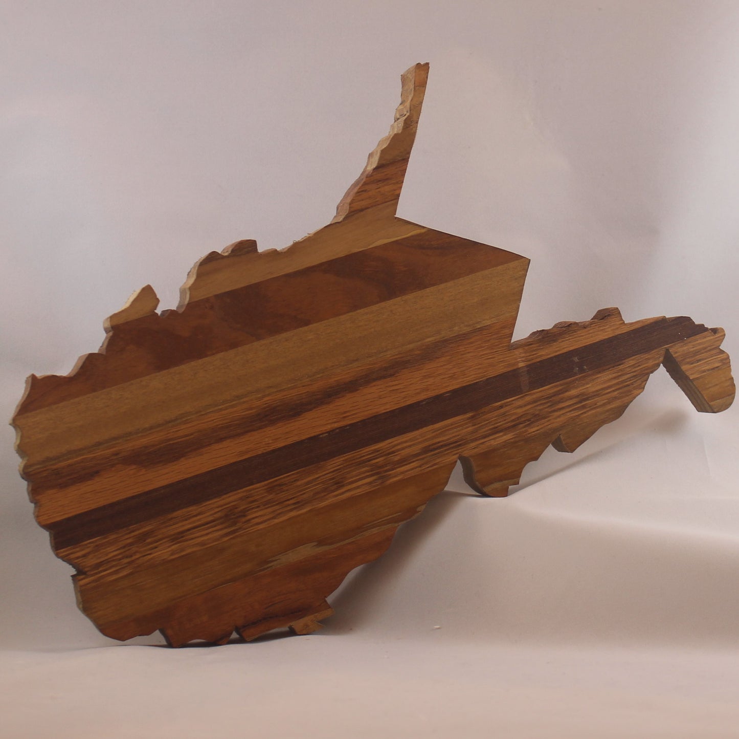 Variegated wood cutout of the shape of the state of West Virginia. There is a keyhole cut in the back for hanging. It is approximately 11" x 12." Add $10 for CUSTOM ENGRAVING