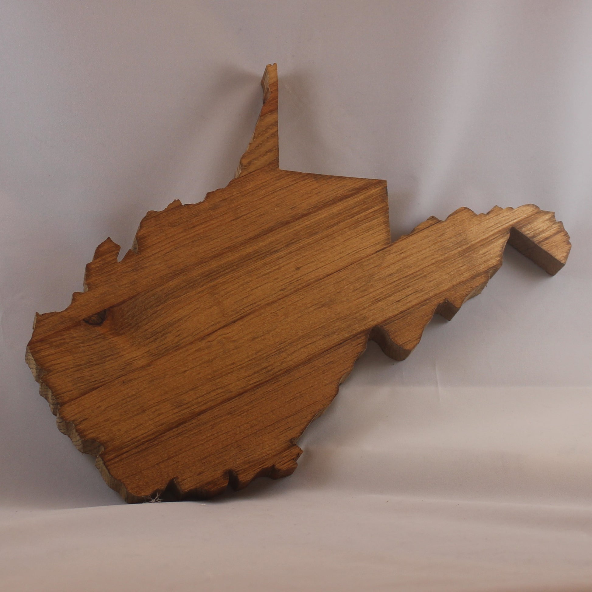 Variegated wood cutout of the shape of the state of West Virginia. There is a keyhole cut in the back for hanging. It is approximately 11" x 12." Add $10 for CUSTOM ENGRAVING