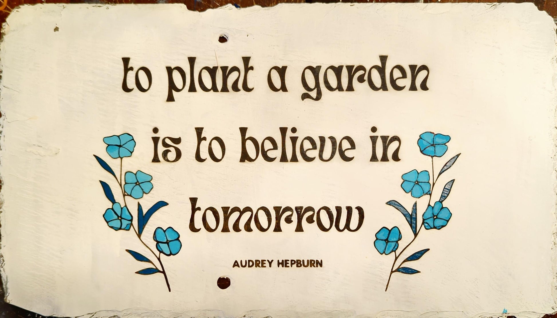 Painted and laser etched slate sign, "to plant a garden is to believe in tomorrow - Audrey Hepburn." white with blue flowers approximately 10" x 16"