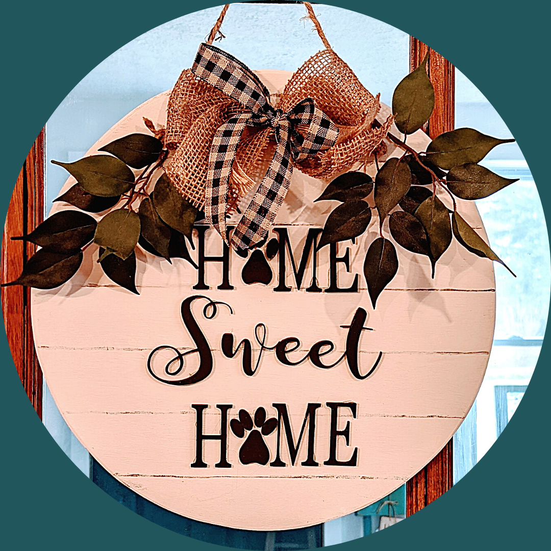 Round white wooden "Home Sweet Home" sign with paw prints, bow, and greenery.