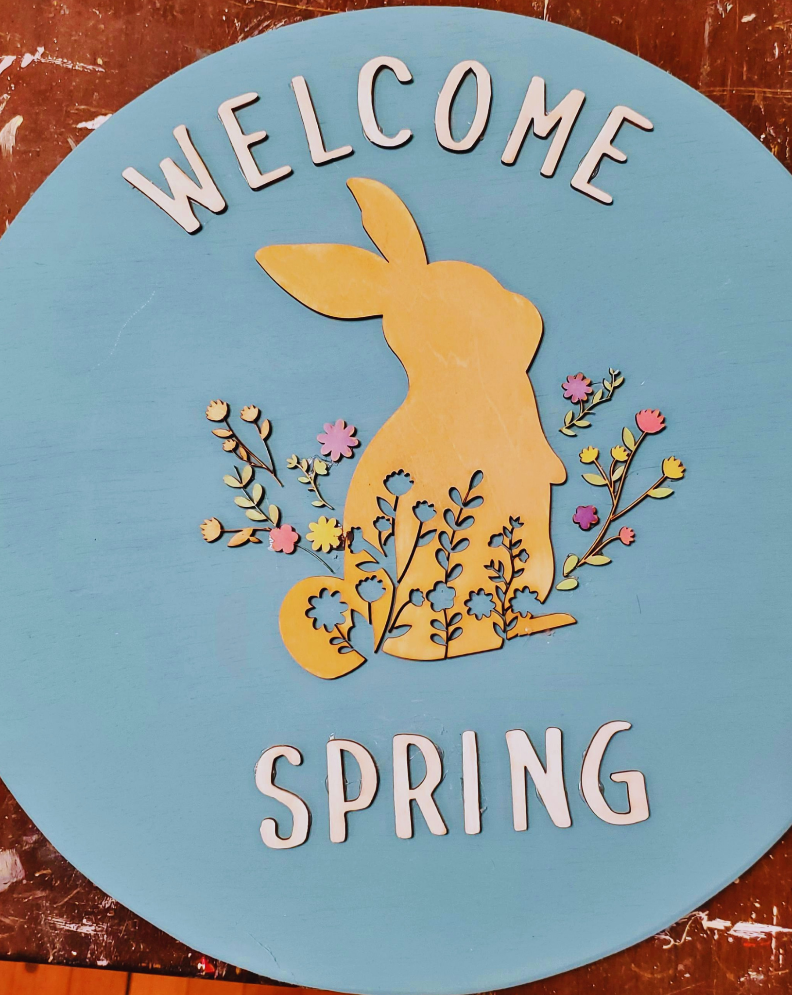 Laser cut "Welcome Spring" and a laser cut bunny with wildflowers. Paint the round sign and all the cut items whatever colors you want to welcome spring!