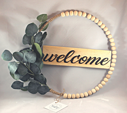 Beautiful raw wood beaded hoop wreath with eucalyptus. Laser engraved wood sign says "welcome." 14" wide.